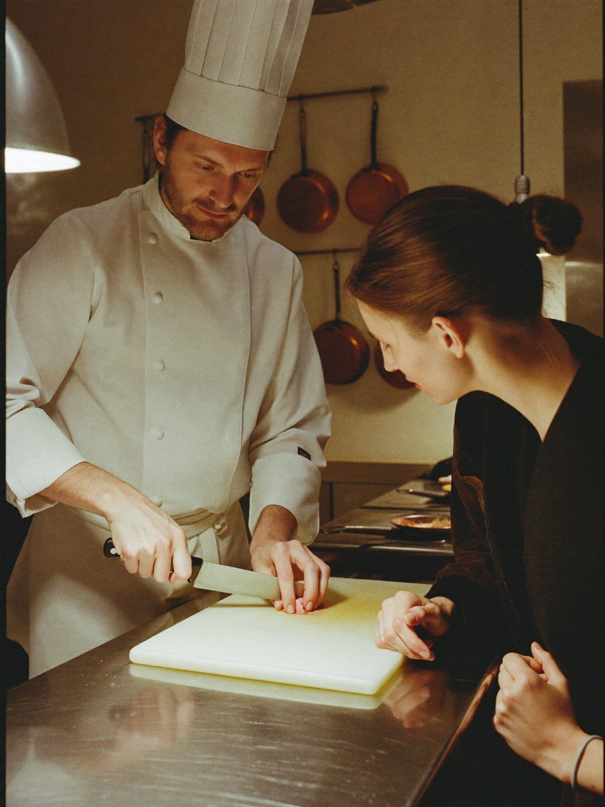 A chef demonstrating knife technique to two students