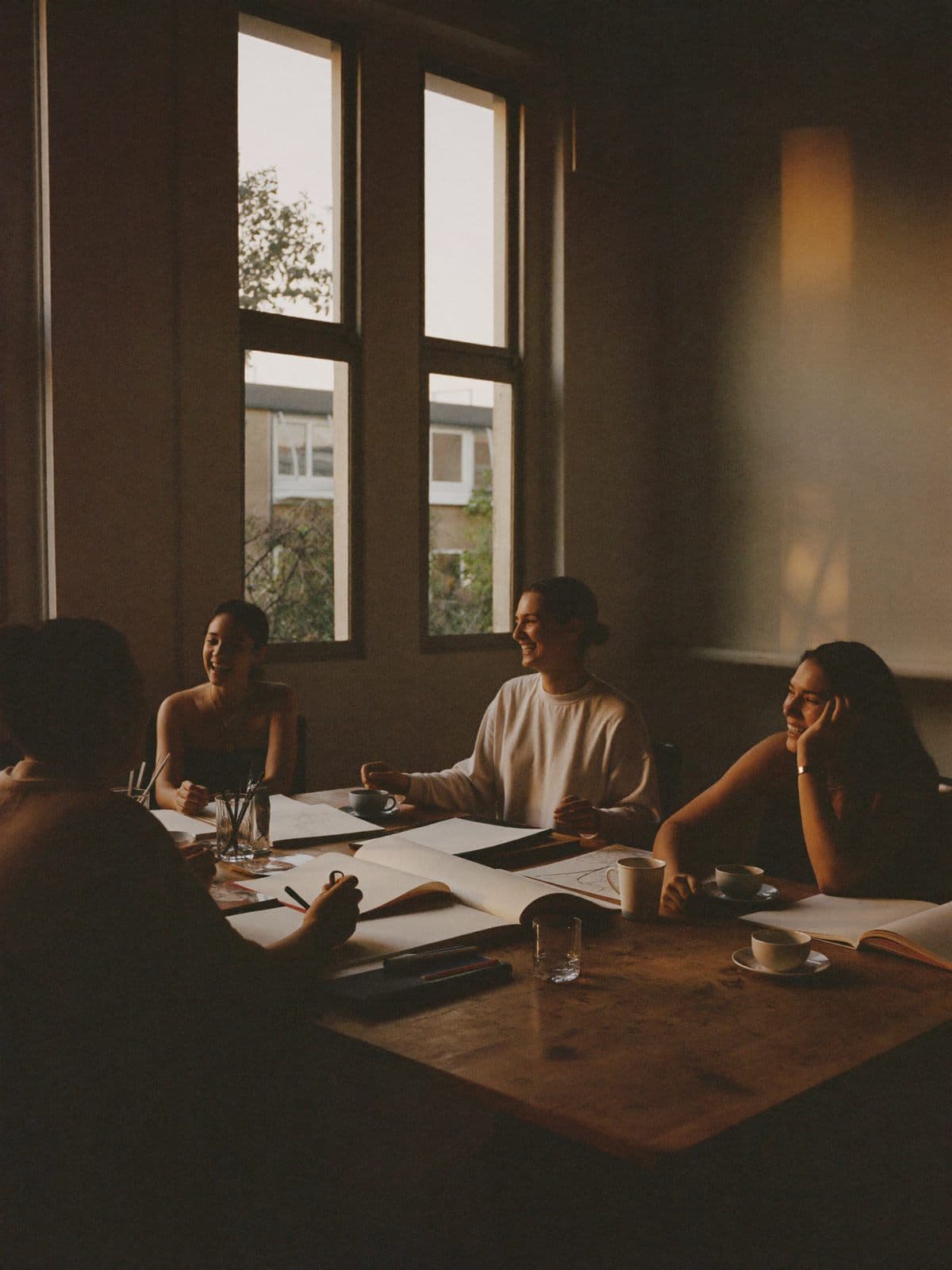 Students laughing around a worktable during an evening workshop